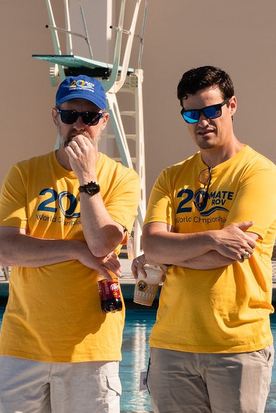 Two men wearing yellow MATE 20th Anniversary T-shirts
